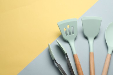 Photo of Different spatulas and tongs on color background, flat lay. Space for text