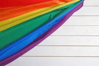 Bright rainbow gay flag on wooden background, top view with space for text. LGBT community