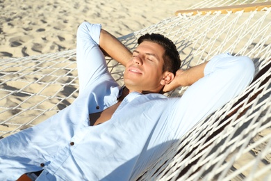 Photo of Handsome man relaxing in hammock on beach