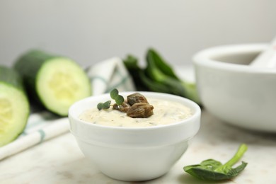 Creamy caper sauce in bowl on white marble table, closeup