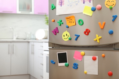 Sheets of paper, child's drawing and magnets on refrigerator door in kitchen. Space for text