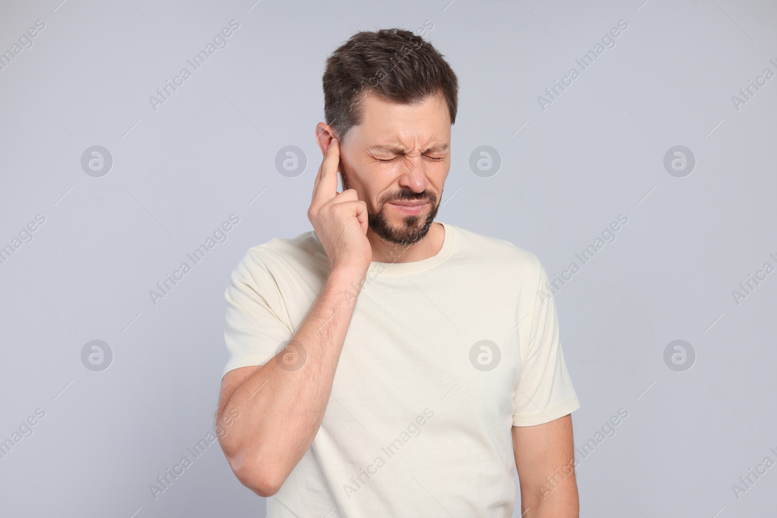 Photo of Man suffering from ear pain on grey background