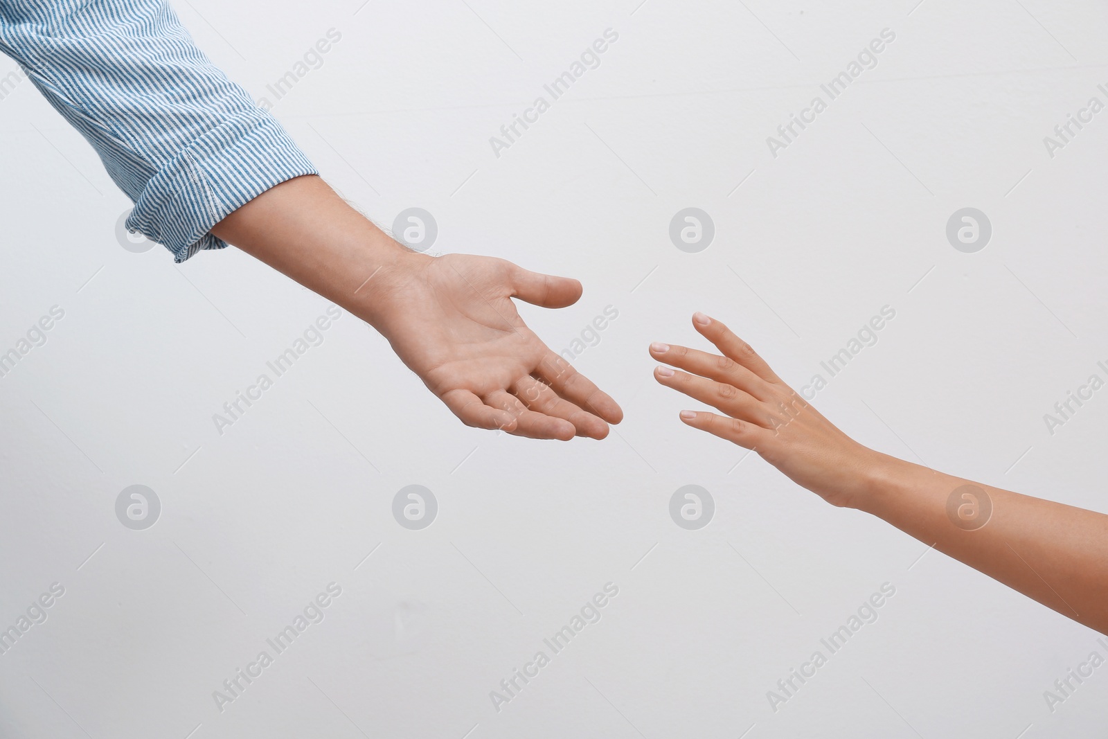 Photo of Man and woman giving each other hands on light background. Concept of support and help