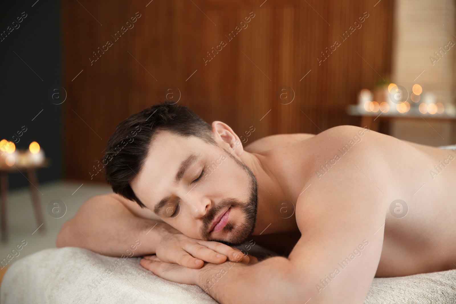 Photo of Handsome man relaxing on massage table in spa salon