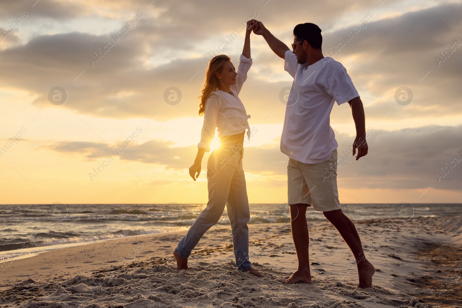 Photo of Happy couple dancing on beach at sunset