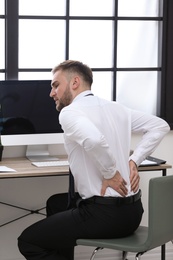 Photo of Businessman suffering from back pain at workplace