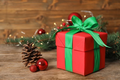 Photo of Red gift box with green bow and Christmas decor on wooden table