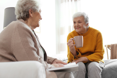 Photo of Elderly women spending time together in bedroom. Senior people care