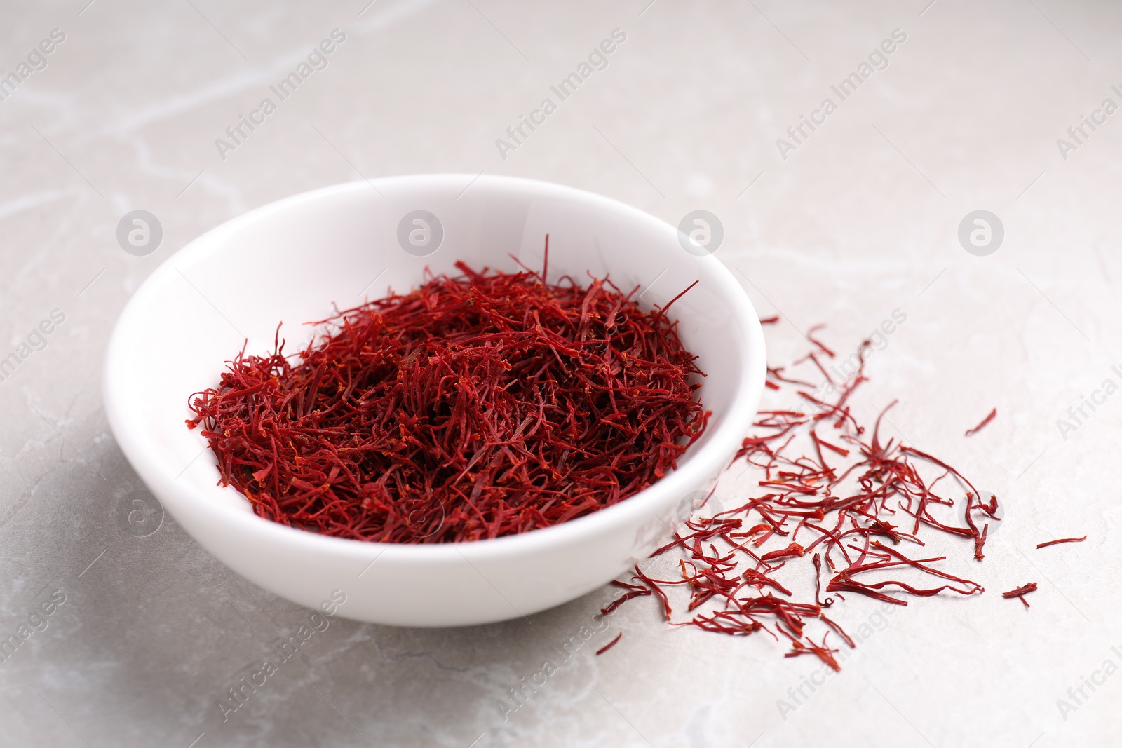 Photo of Aromatic saffron in bowl on light gray table