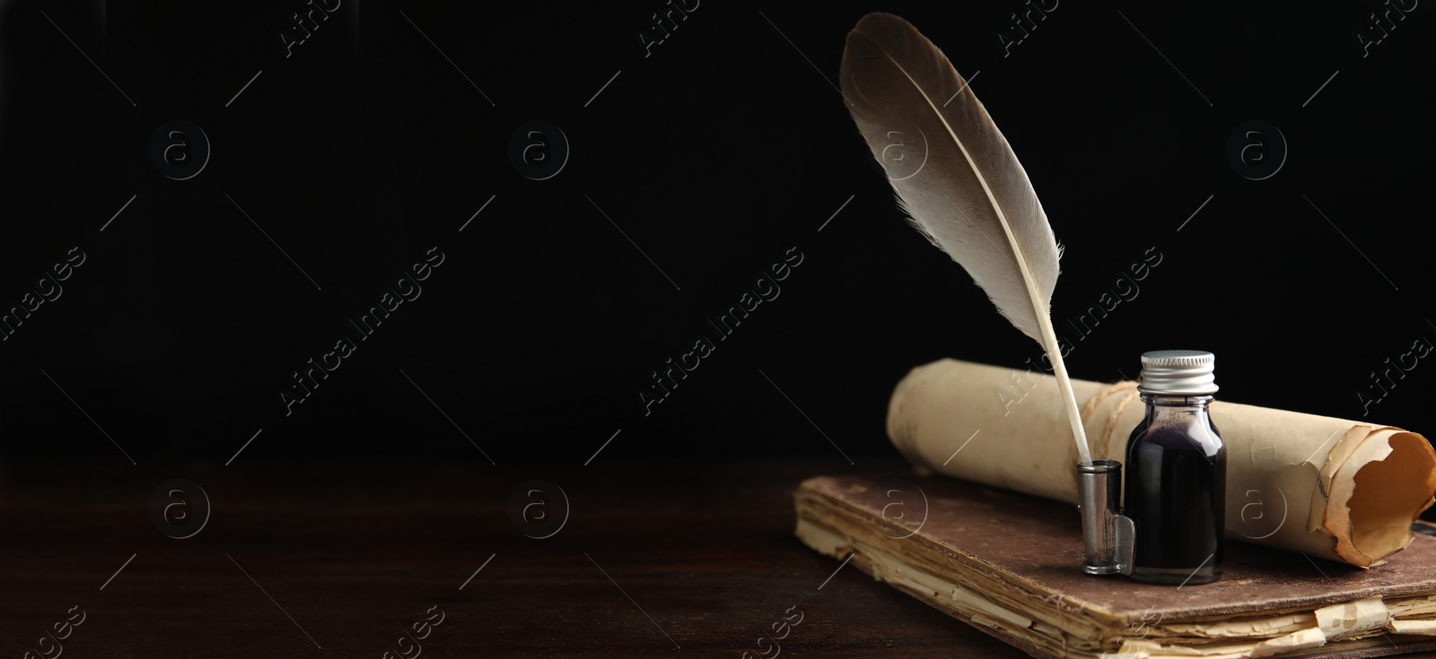 Image of Quill, bottle of ink, old book and parchment scroll on wooden table, space for text. Banner design