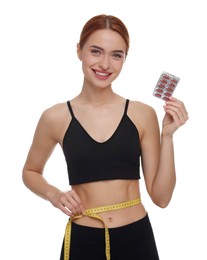 Photo of Slim woman holding pills and measuring waist with tape on white background. Weight loss