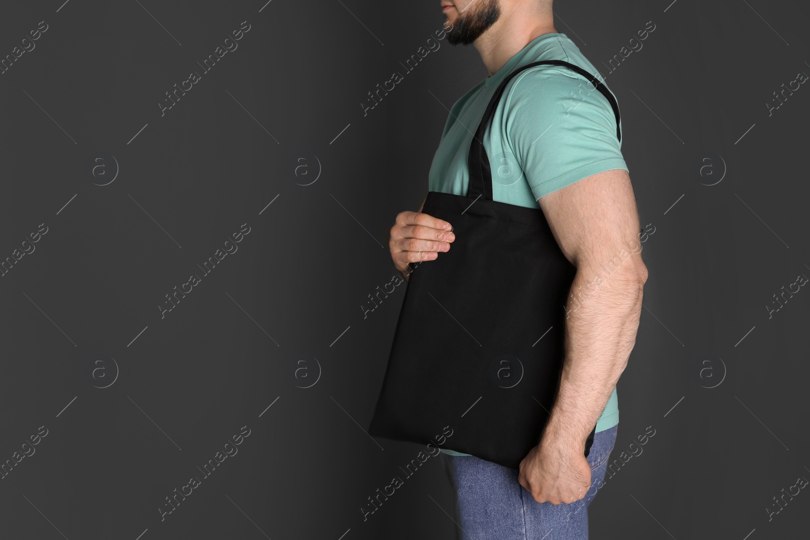 Photo of Man with cotton shopping eco bag on grey background. Mockup for design