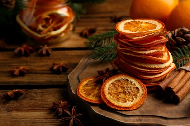 Photo of Dry orange slices, anise stars and cinnamon sticks on wooden table, space for text