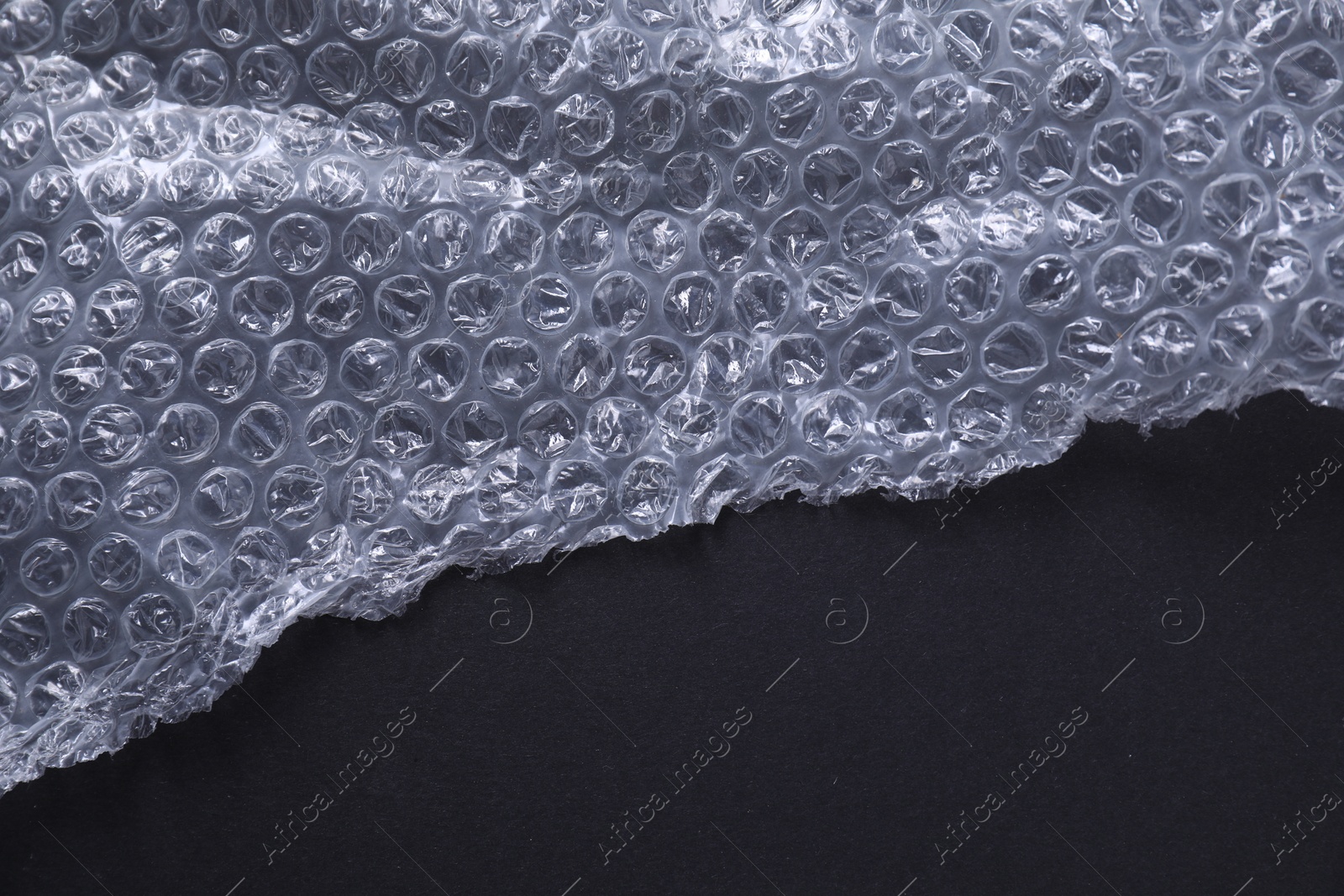 Photo of Transparent bubble wrap on black background, top view. Space for text