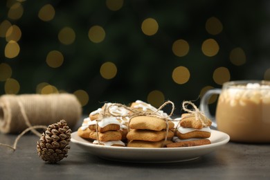 Photo of Decorated cookies and hot drink on grey table against blurred Christmas lights
