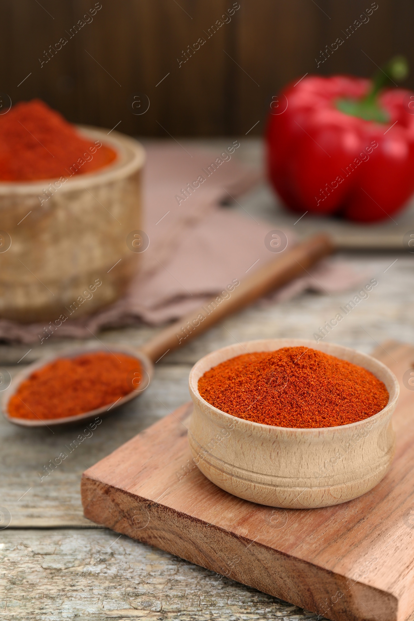 Photo of Bowl with aromatic paprika powder on old wooden table