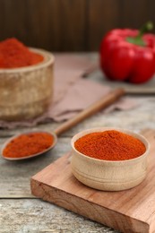 Photo of Bowl with aromatic paprika powder on old wooden table