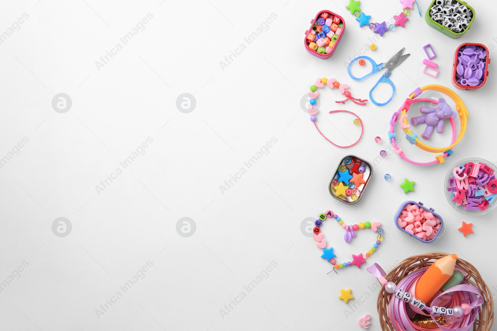 Photo of Kid's handmade beaded jewelry and different supplies on white background, top view. Space for text