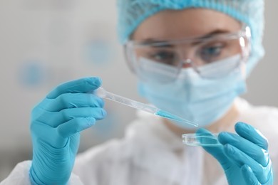 Scientist dripping sample into Petri dish in laboratory, selective focus
