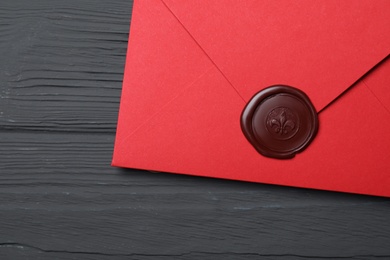 Photo of Red envelope with wax seal on black wooden background, top view