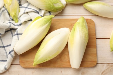 Photo of Raw ripe chicories on wooden table, top view