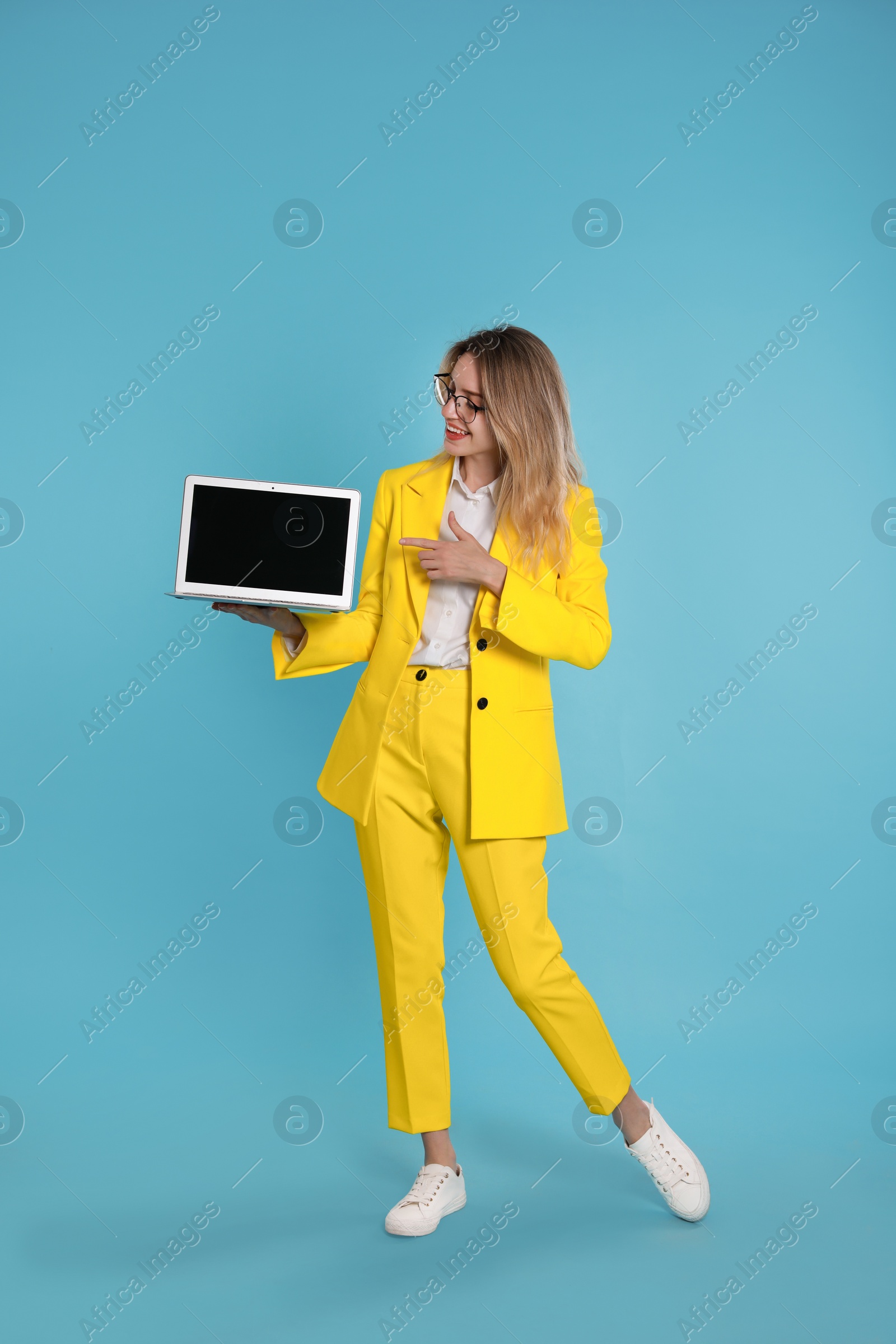 Photo of Young woman with modern laptop on light blue background