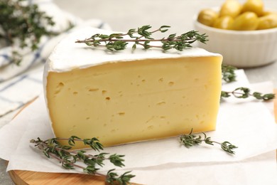 Photo of Piece of tasty camembert cheese and thyme on table, closeup
