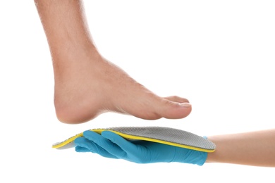 Photo of Orthopedist fitting insole on patient's foot against white background, closeup