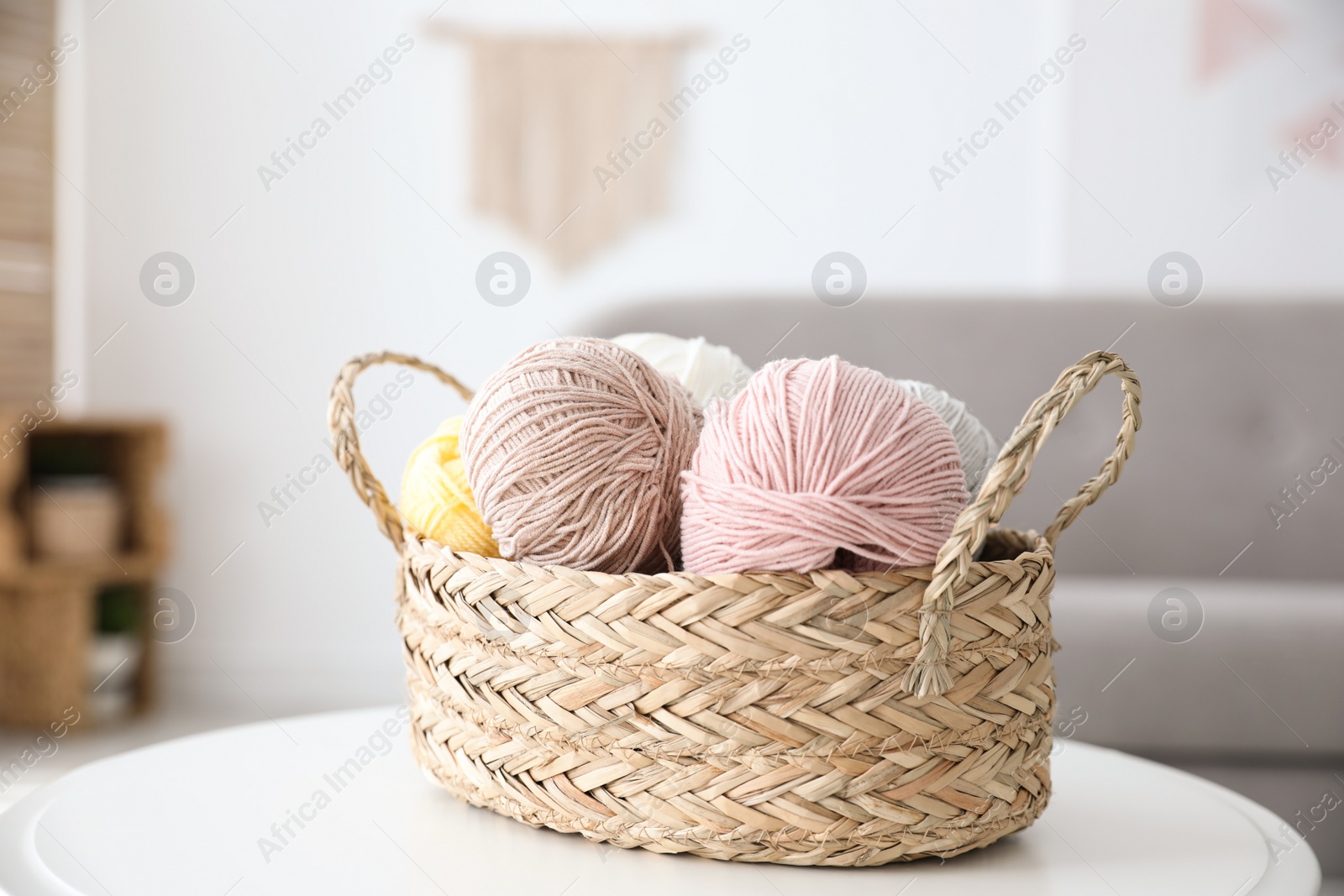 Photo of Wicker basket with clews on table indoors. Engaging in hobby