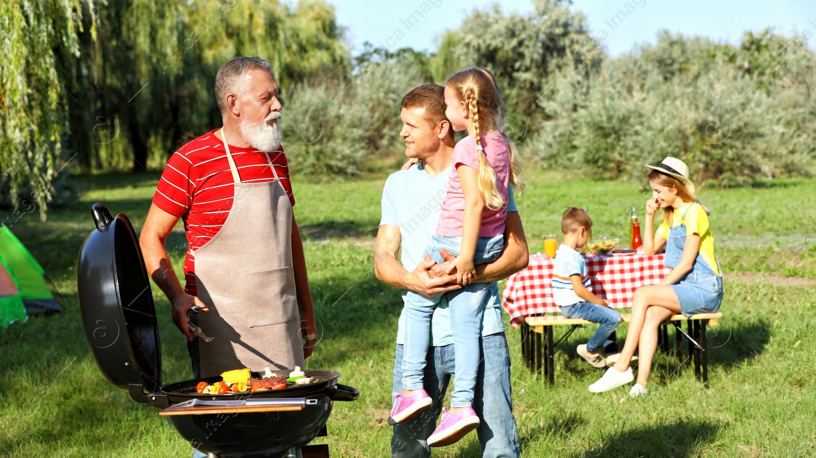 Photo of Happy family having barbecue in park on sunny day