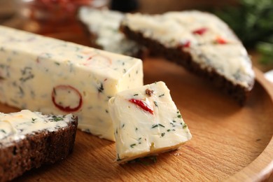 Photo of Tasty butter with dill and chili pepper on wooden plate, closeup