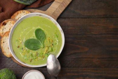 Delicious broccoli cream soup with basil and pumpkin seeds served on wooden table, flat lay. Space for text