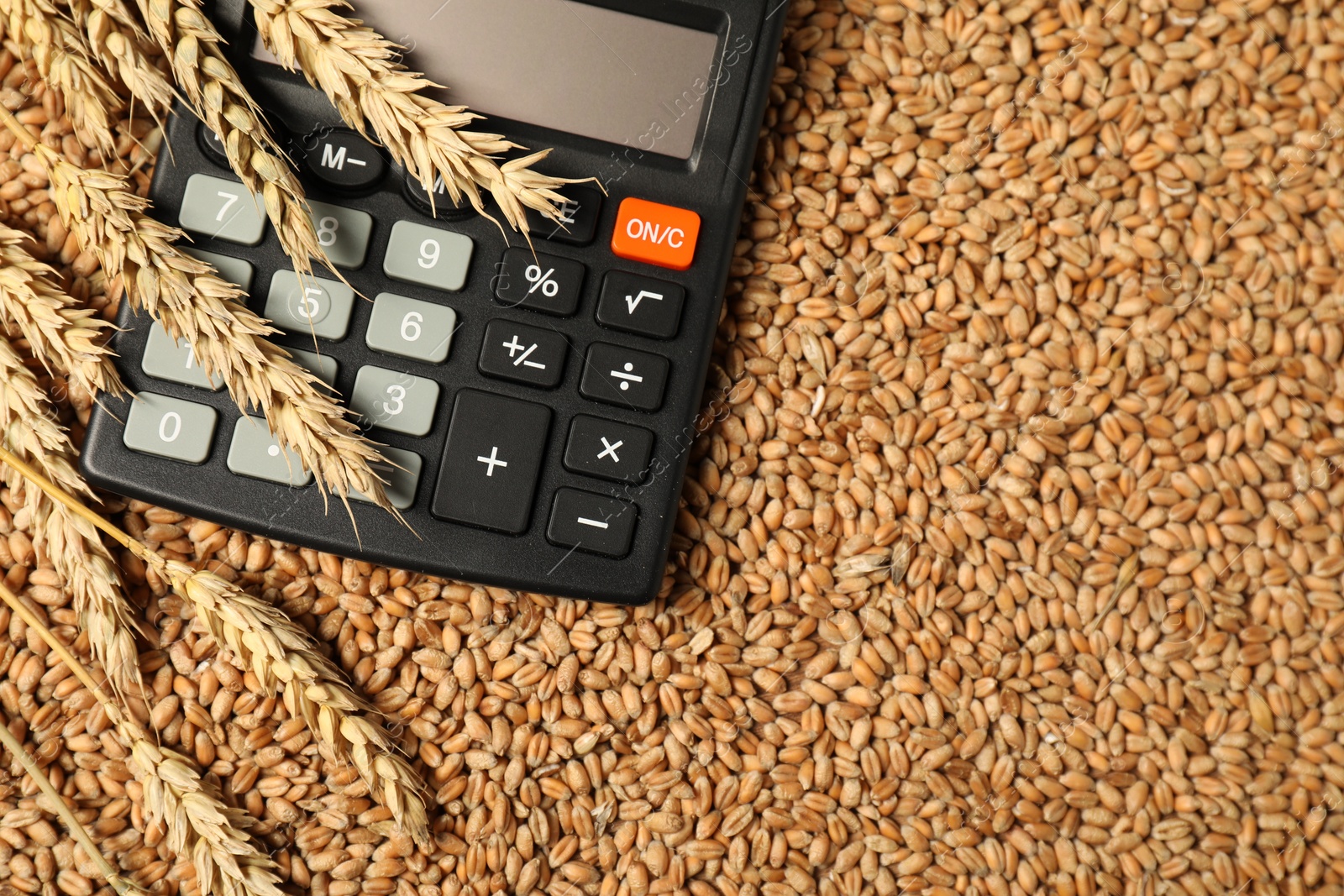 Photo of Calculator and wheat ears on grains, top view. Agricultural business