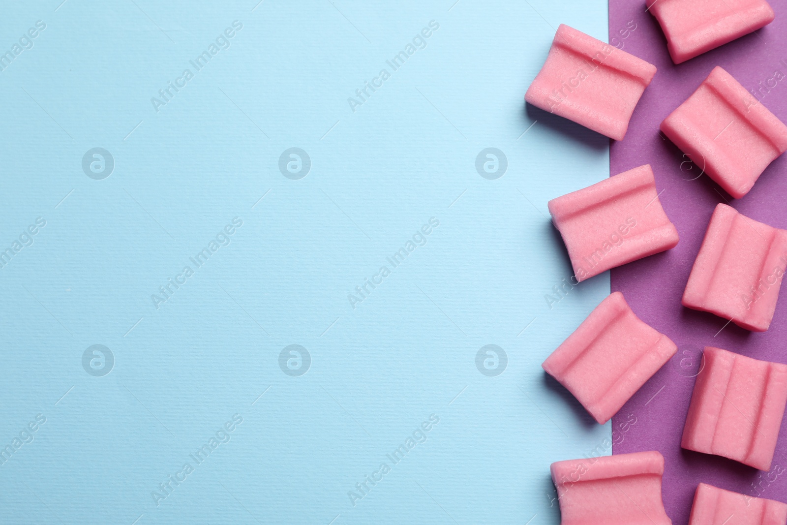 Photo of Tasty pink chewing gums on color background, flat lay. Space for text