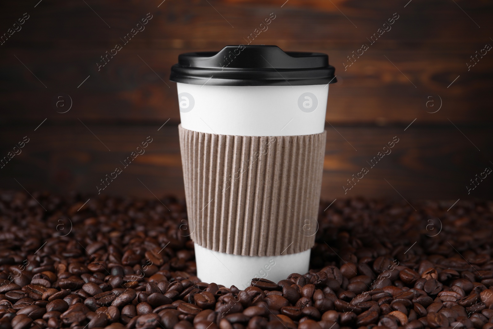 Photo of Coffee to go. Paper cup and roasted beans against wooden background, closeup