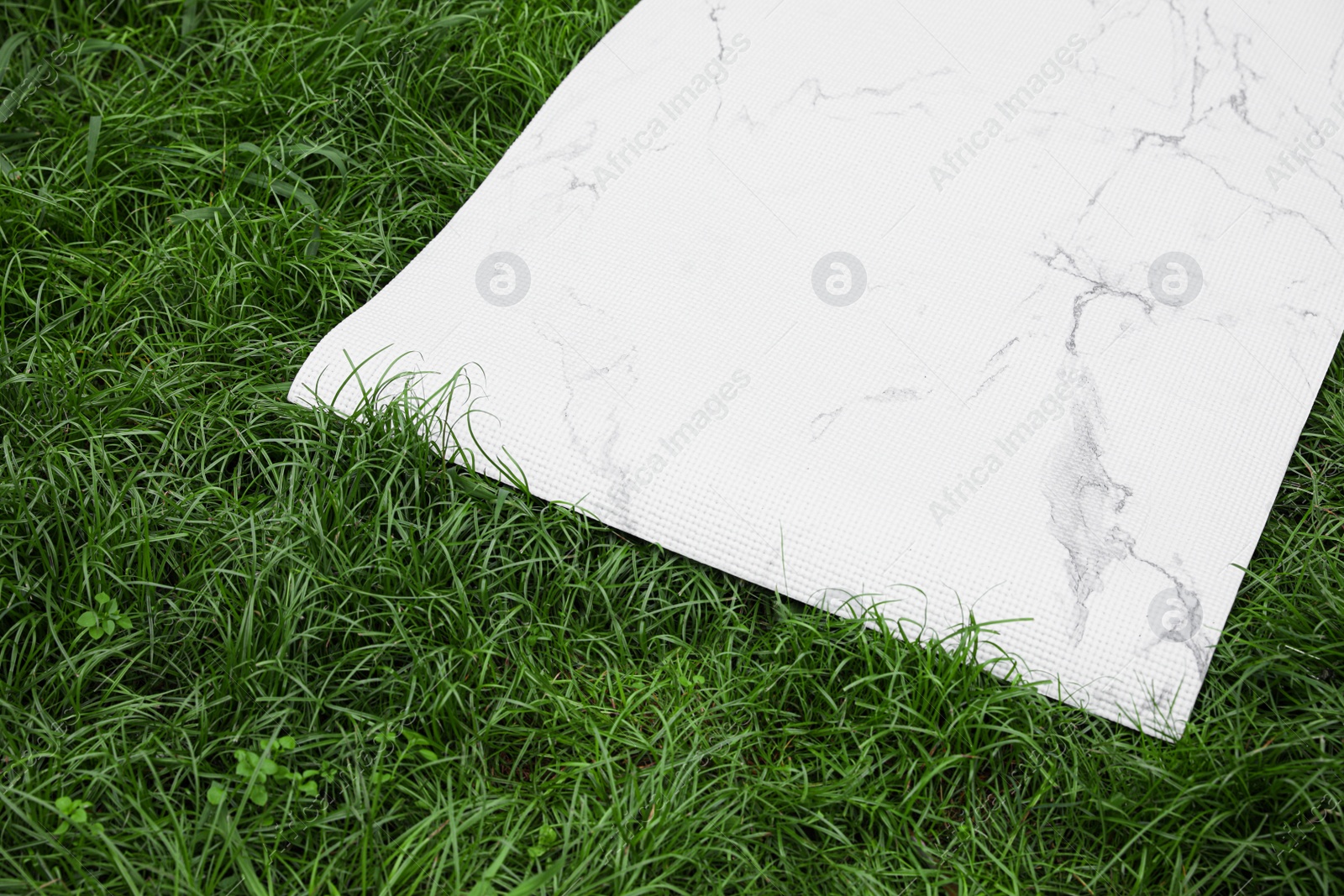 Photo of White karemat or fitness mat on green grass outdoors