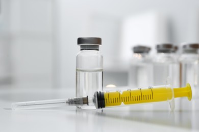 Photo of Syringe and vial of medicine on white table, closeup