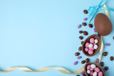 Photo of Flat lay composition with tasty chocolate eggs and candies on light blue background. Space for text