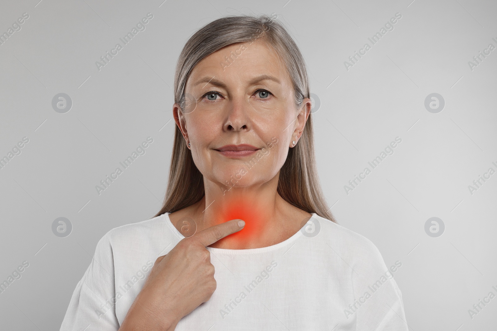 Image of Endocrine system. Senior woman doing thyroid self examination on light grey background