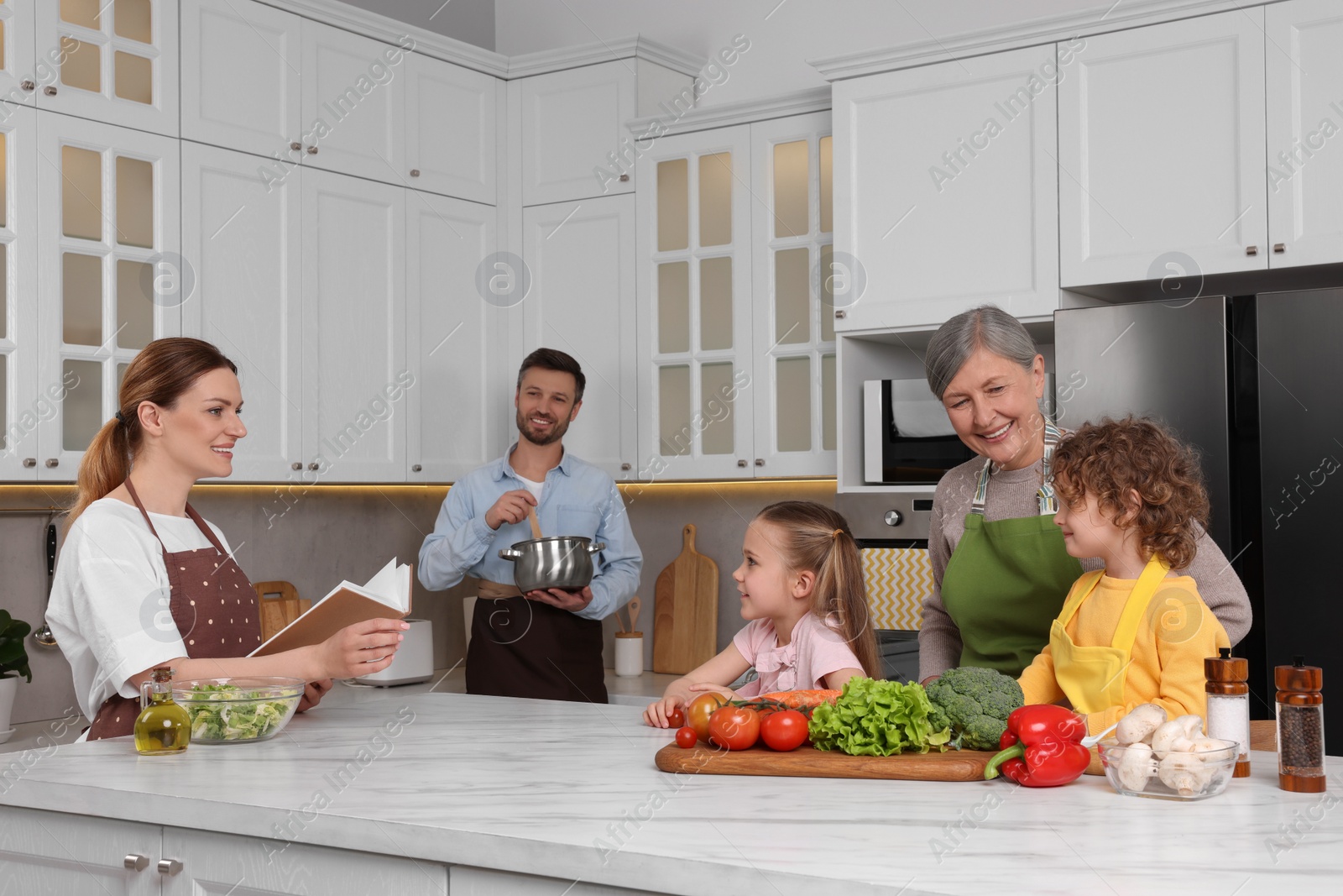 Photo of Family cooking by recipe book in kitchen