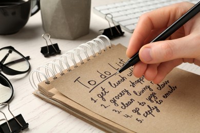 Photo of Woman checking to do list at wooden table, closeup