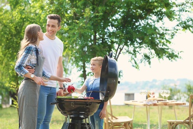 Happy family having barbecue with modern grill outdoors