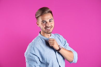 Young man with trendy hairstyle on color background