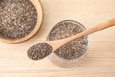 Photo of Glass of water with chia seeds and spoon on wooden background, top view