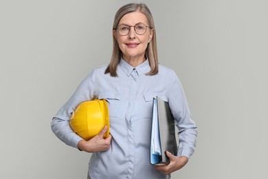 Photo of Architect with hard hat and tube on grey background