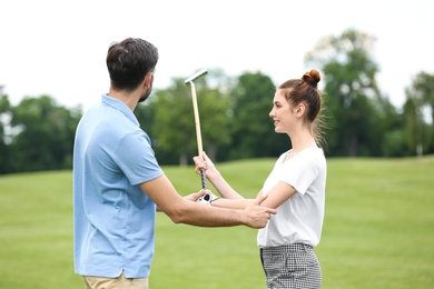 Photo of Coach teaching woman to play golf on green course
