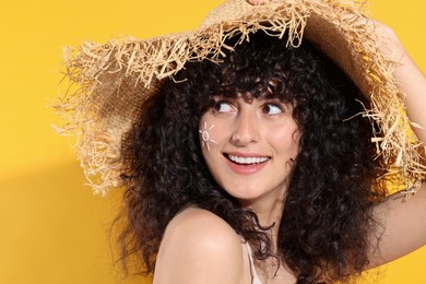 Photo of Beautiful happy woman in straw hat with sun protection cream on her face against orange background