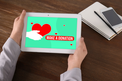 Image of Donations concept. Woman with tablet at wooden table, closeup
