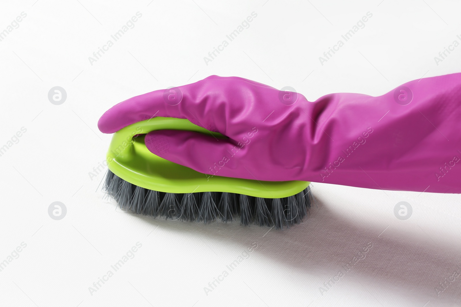 Photo of Woman in purple gloves cleaning white mattress with brush, closeup