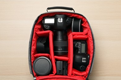 Photo of Professional photography equipment in backpack on wooden table, top view